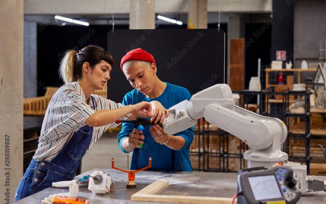 Classmates Working With Robotic Equipment At Desk