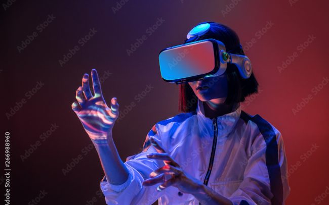 Excited young woman touching air while having virtual reality experience in neon light