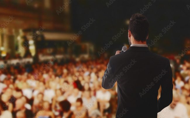 Rear view of speaker giving a talk on corporate Business Conference. Audience at the conference hall.